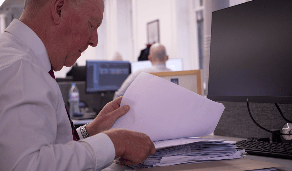 Man sat at desk looking through a stack of papers